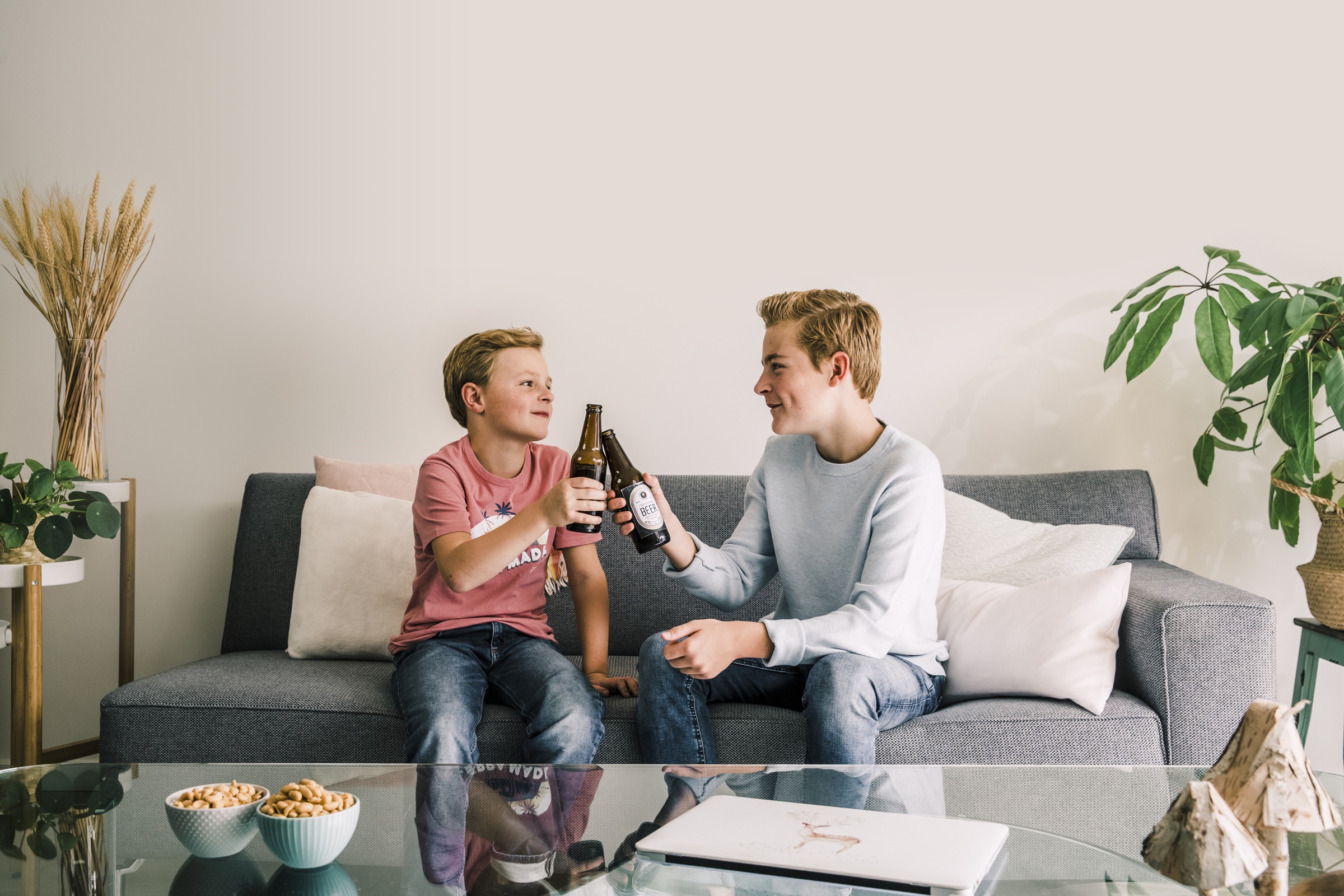 Twee jongens op dezelfde bank proosten met een flesje, precies zoals de mannen.